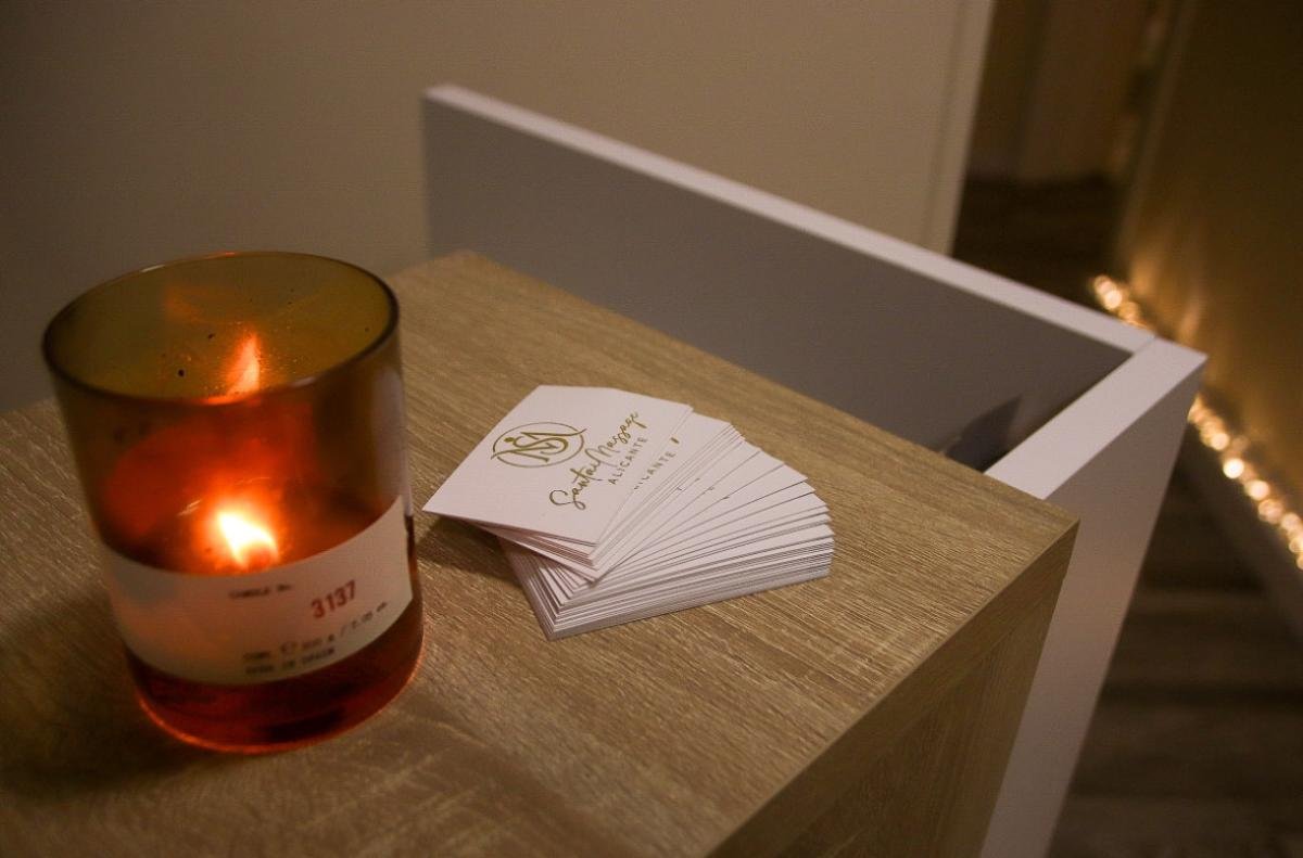 Detalle de recepción con vela y tarjetas de Santai Massage Alicante.